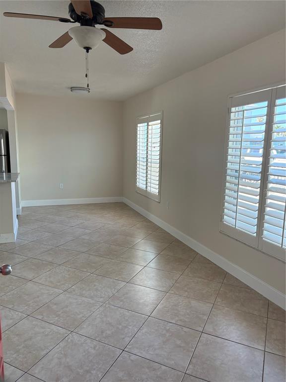 An empty room features beige tile flooring, white walls, plantation shutters, and a ceiling fan — 555 69TH AVENUE UNIT 1, ST PETERSBURG, FL
