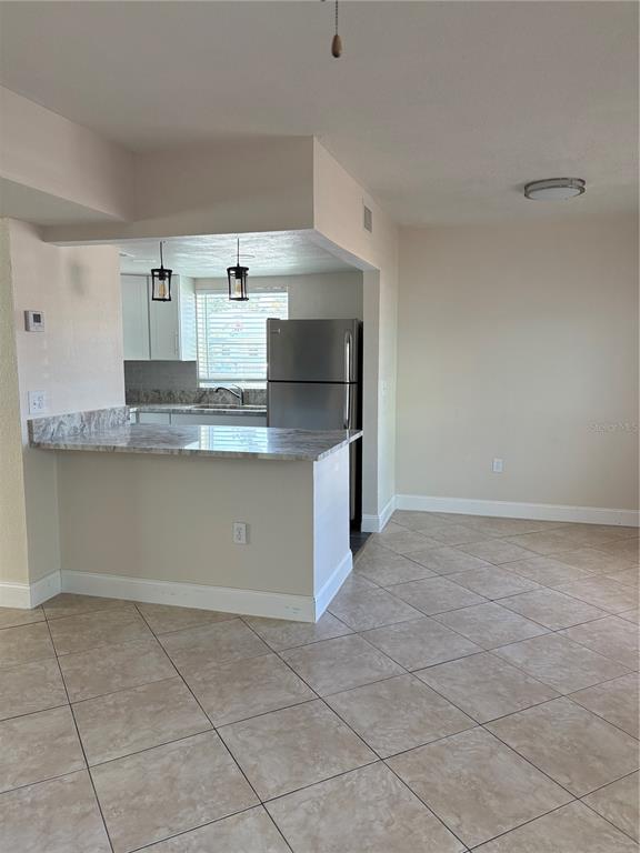 A kitchen with a breakfast bar, stainless steel refrigerator, and tiled floors — 555 69TH AVENUE UNIT 1, ST PETERSBURG, FL