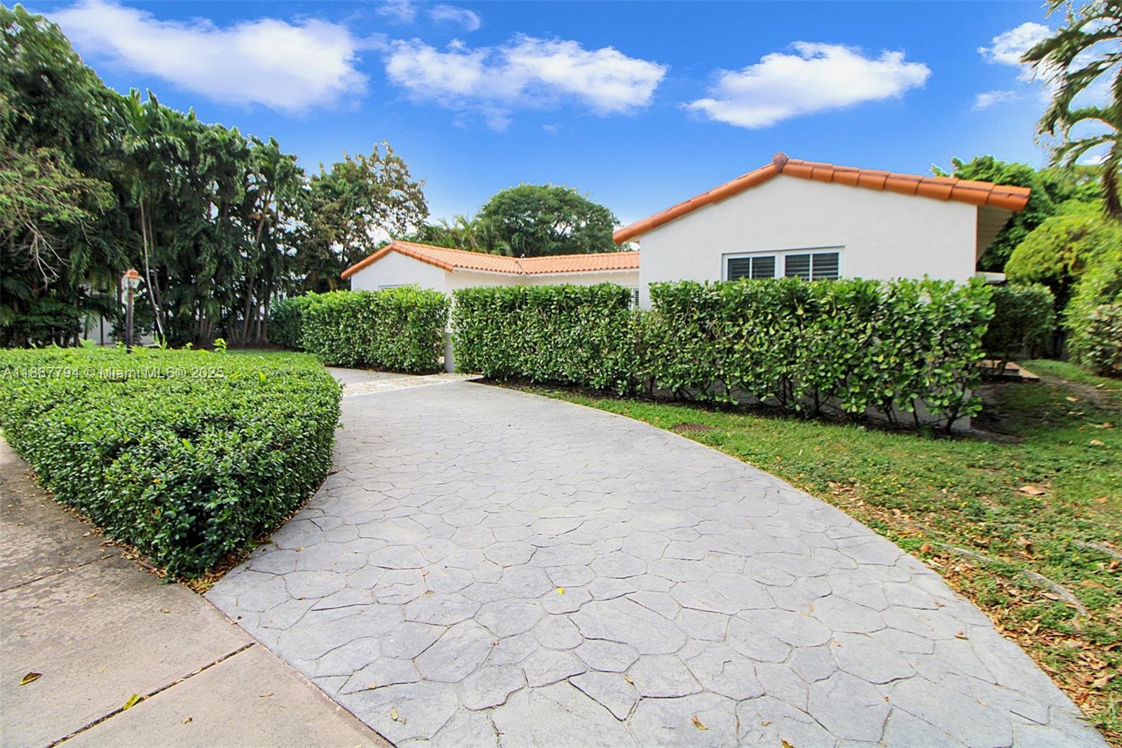 A white house with a tile roof sits behind a large, manicured hedge — 1110 Wallace St, Coral Gables FL 33134, CORAL GABLES, FL