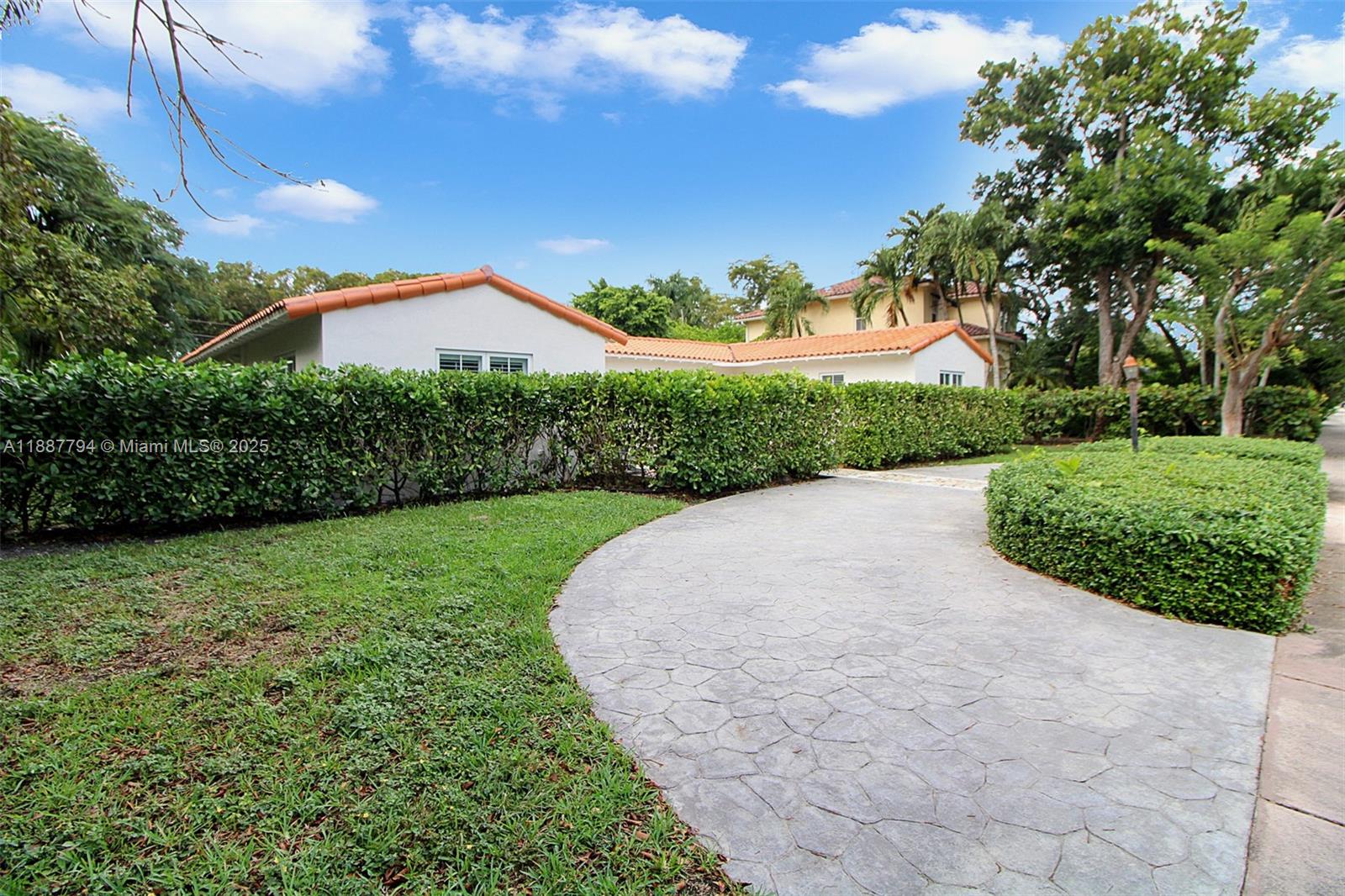 A paved driveway leads to a white house with a terracotta tile roof behind hedges — 1110 Wallace St, Coral Gables FL 33134, CORAL GABLES, FL