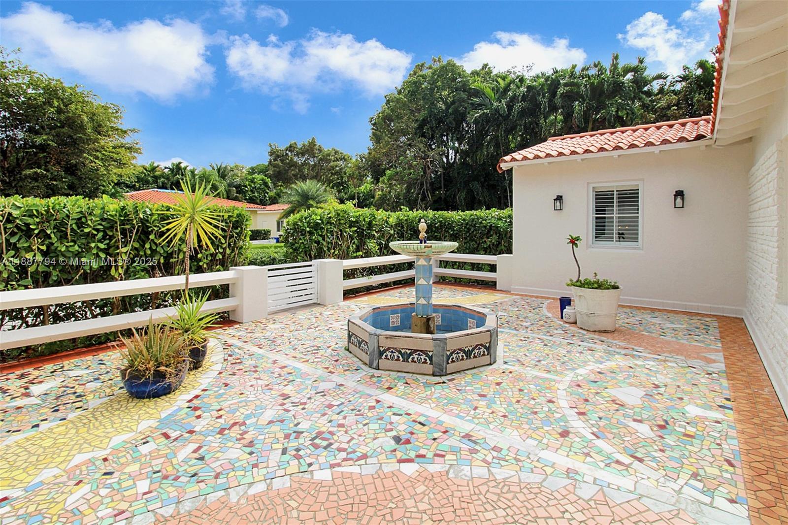 A patio features a decorative mosaic tile floor, a central fountain, and surrounding greenery — 1110 Wallace St, Coral Gables FL 33134, CORAL GABLES, FL