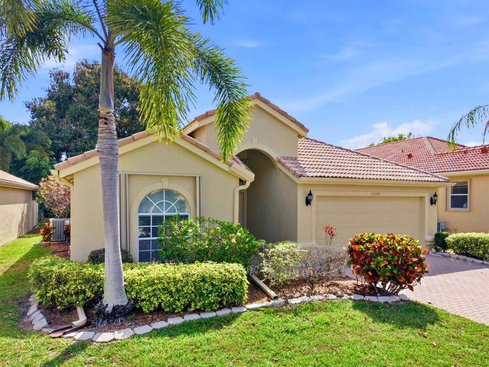 A single-story tan stucco house with a tile roof, arched window, and palm tree — 10740 Grande Palladium Way, Boynton Beach FL 33436, BOYNTON BEACH, FL