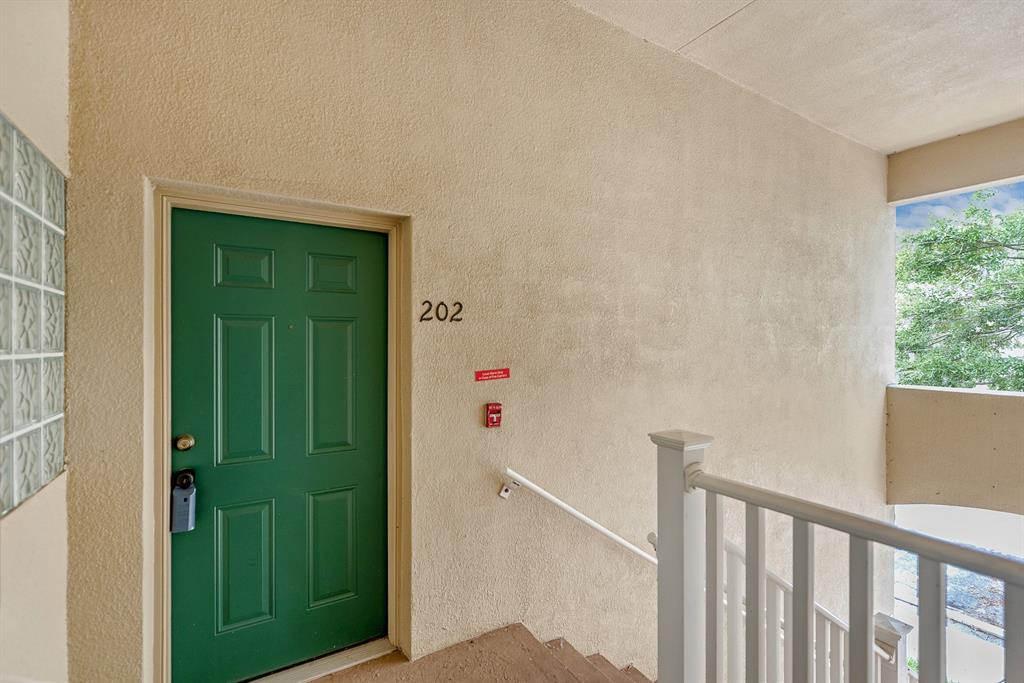 A green apartment door labeled 202 is located at the top of an outdoor staircase — 6014 PORTSDALE PLACE UNIT 202, RIVERVIEW, FL