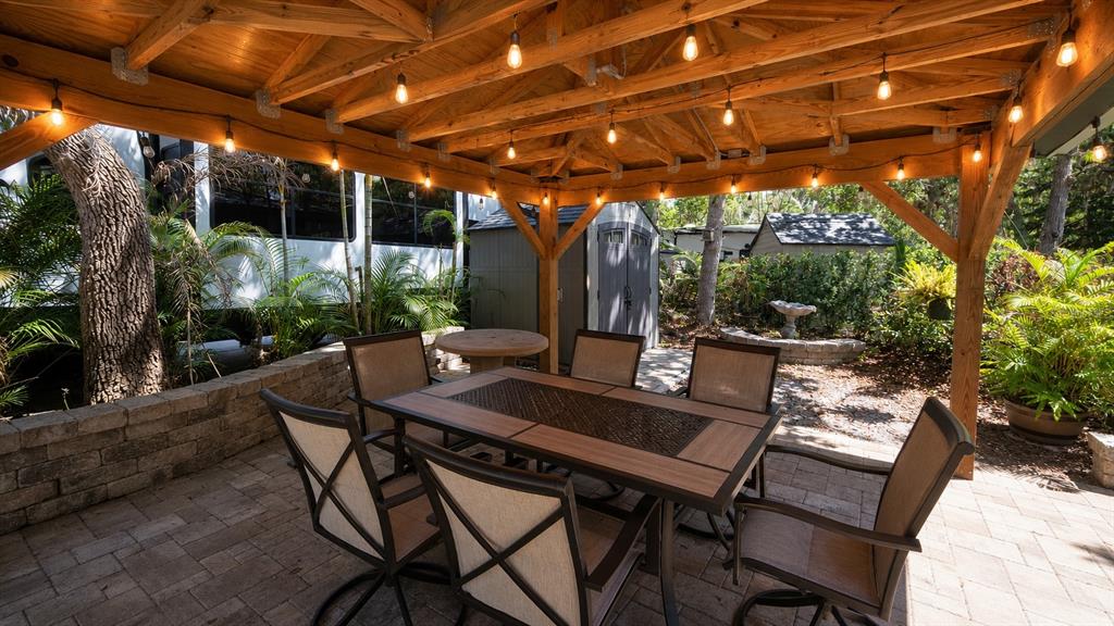 A covered patio features a dining set on a paver floor under a wooden pergola — 234 STALLION LANE, RIVER RANCH, FL