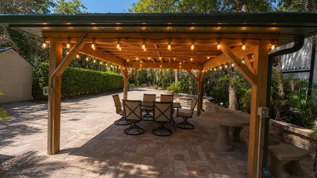A covered wooden pergola features string lights over a patio with dining furniture — 234 STALLION LANE, RIVER RANCH, FL
