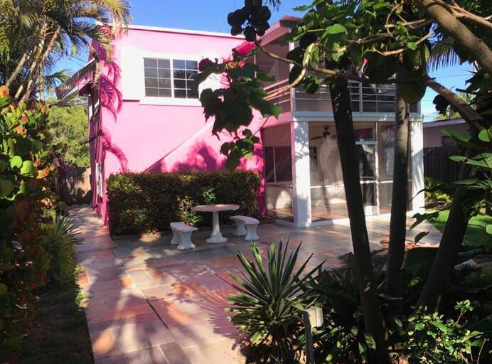 A bright pink two-story house features a screened-in porch and a stone patio with seating — 12 S Ocean Breeze # 2, FL 33460, FL