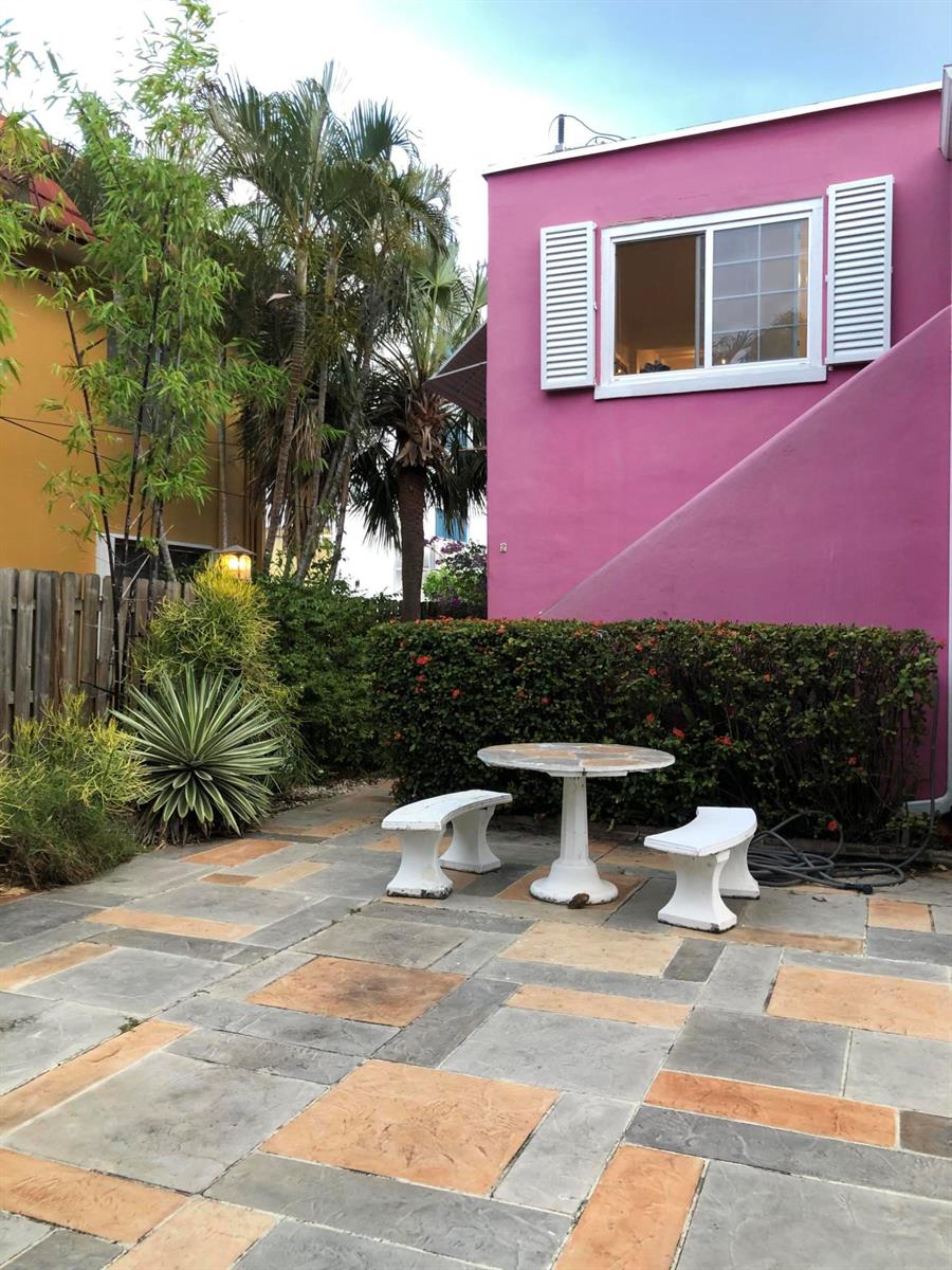 A patio with a stone-tiled floor, a small table, and two benches beside a pink building — 12 S Ocean Breeze # 2, FL 33460, FL
