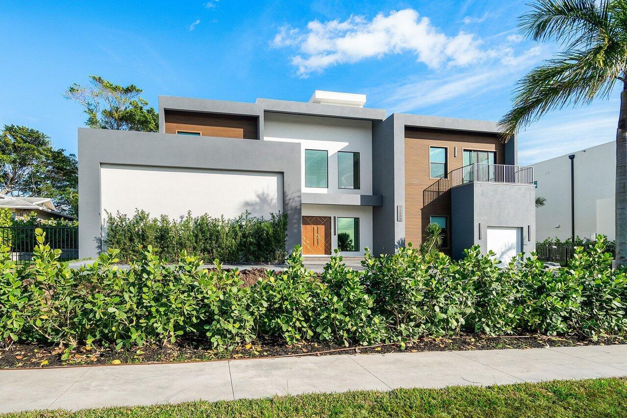 A modern two-story house with gray and wood-paneled exterior walls and a front hedge — 13480 Us Highway 1, Juno Beach FL 33408, JUNO BEACH, FL