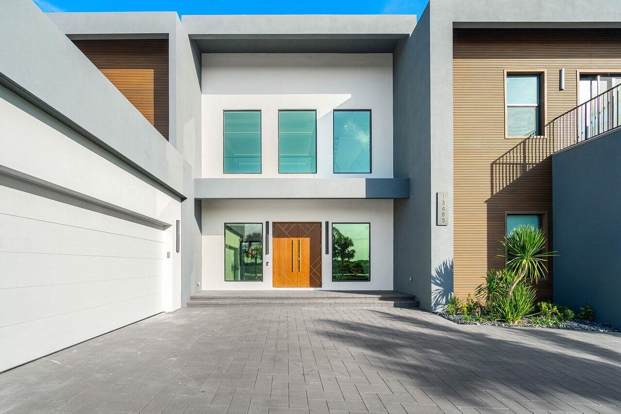 A modern two-story house exterior features a gray facade, wood paneling, and a paved driveway — 13480 Us Highway 1, Juno Beach FL 33408, JUNO BEACH, FL