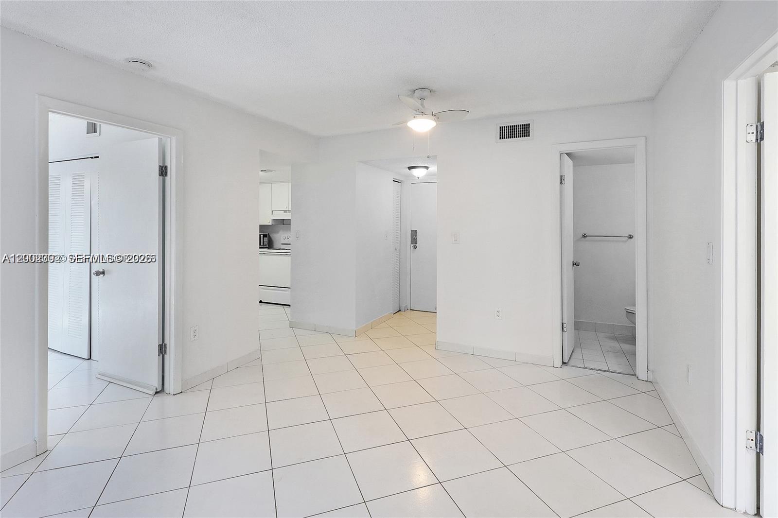 An interior view shows a white-walled room with tiled floors, a ceiling fan, and doorways — 2600 Collins Ave # 405, Miami Beach FL 33140, MIAMI BEACH, FL
