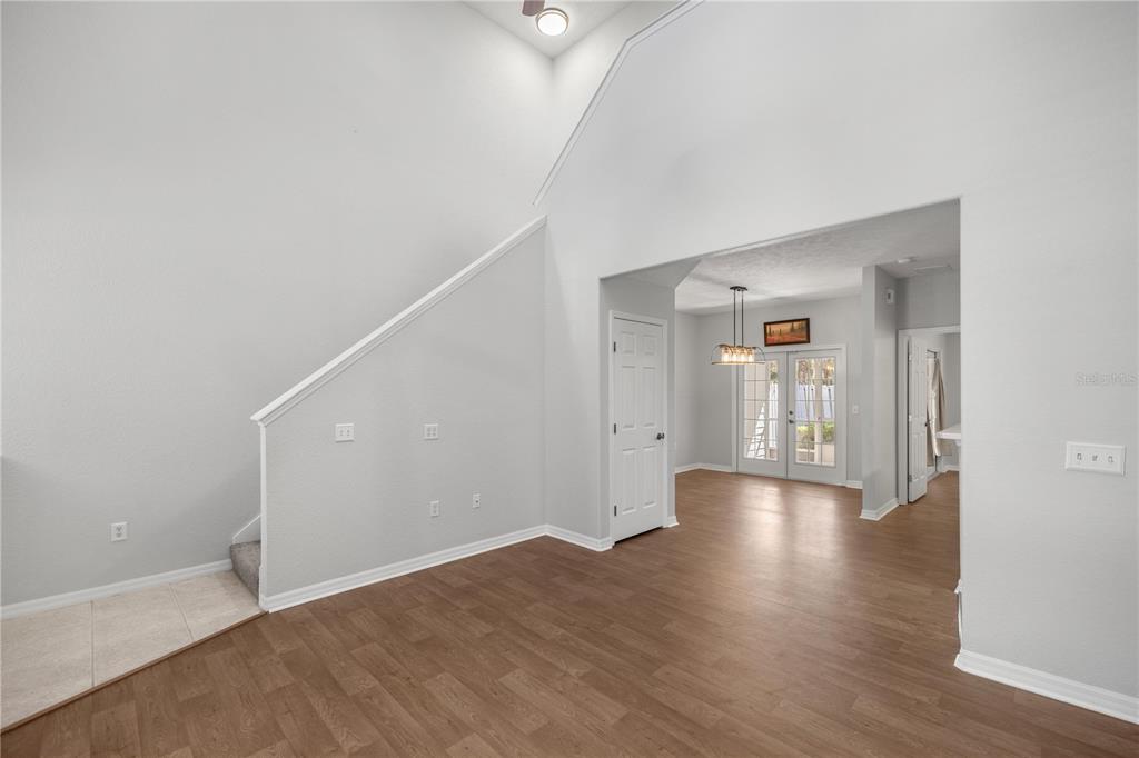 An interior view showing a living area with high ceilings, wood flooring, and a doorway — 231 NE 28TH AVENUE UNIT 103, OCALA, FL