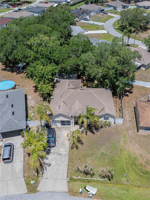 An aerial view shows a single-story house with a driveway, palm trees, and a pool — 427 LARK COURT, KISSIMMEE, FL