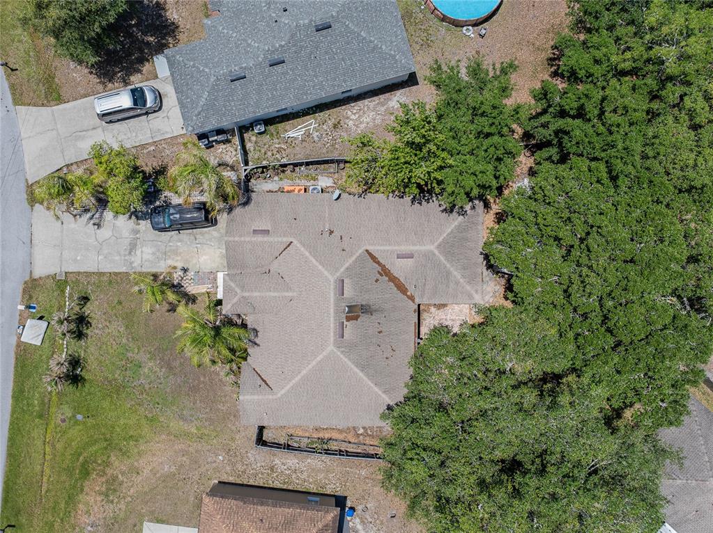 An aerial view shows a house with a shingled roof, driveway, and surrounding trees — 427 LARK COURT, KISSIMMEE, FL