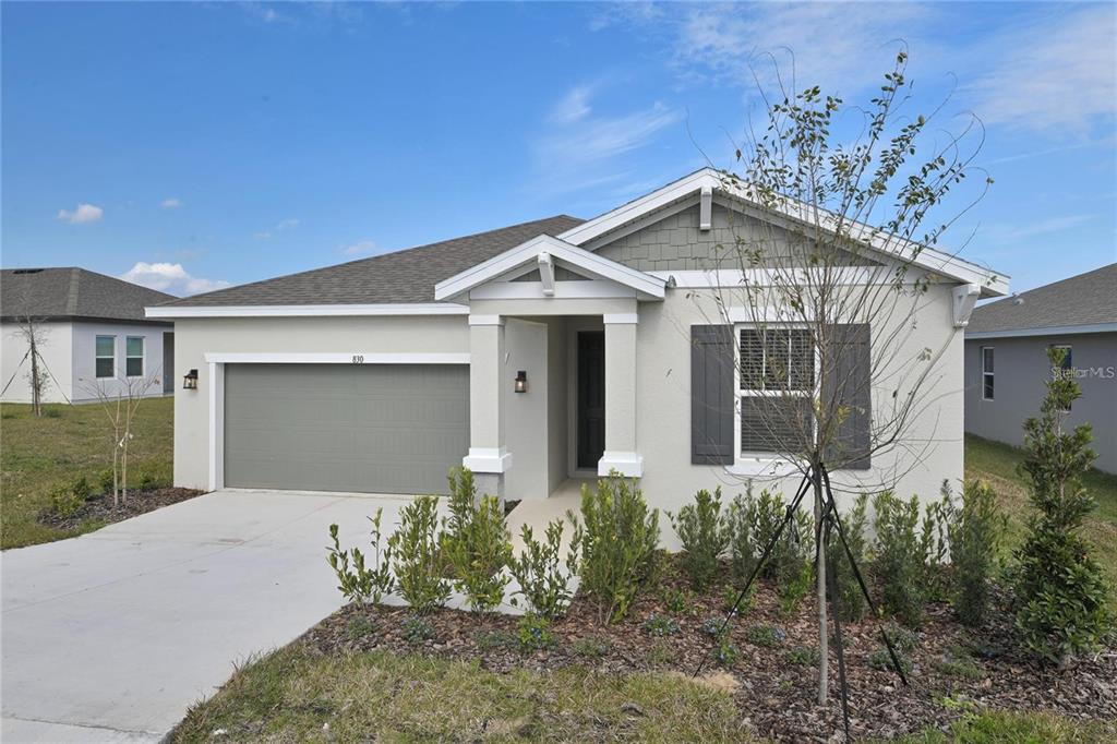 A single-story house with a gray garage, white stucco walls, and a covered entryway — 830 BALLANTYNE DRIVE, LAKE WALES, FL