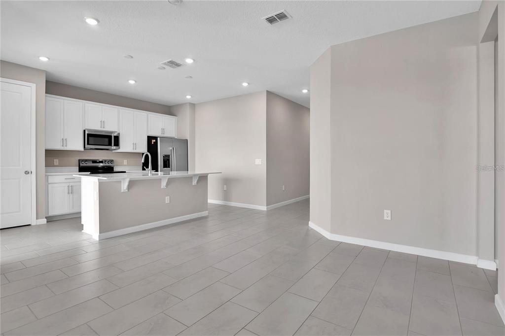 A kitchen with white cabinets, stainless steel appliances, and a breakfast bar island — 830 BALLANTYNE DRIVE, LAKE WALES, FL