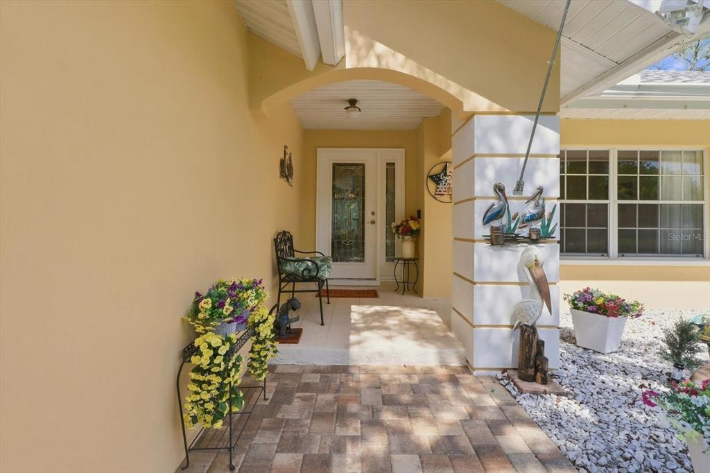 A covered entryway features a paved walkway, a front door with glass, and decorative pelican statues — 6 DUSTY MILLER COURT, HOMOSASSA, FL