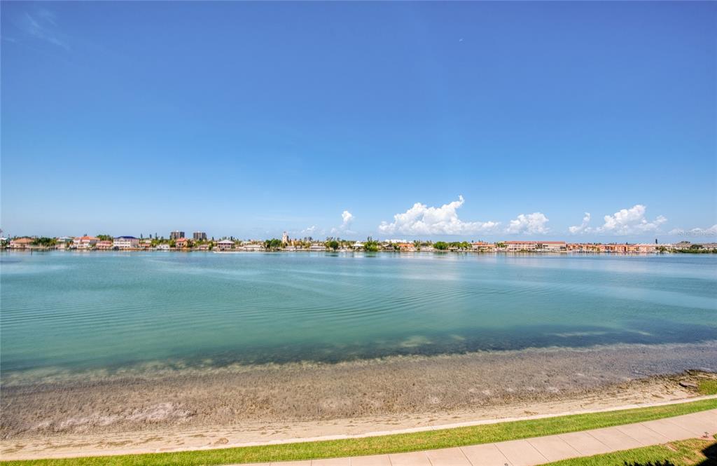A wide view of a calm bay with a sandy shoreline and distant coastal buildings — 7984 SAILBOAT KEY BOULEVARD S UNIT 303, ST PETERSBURG, FL
