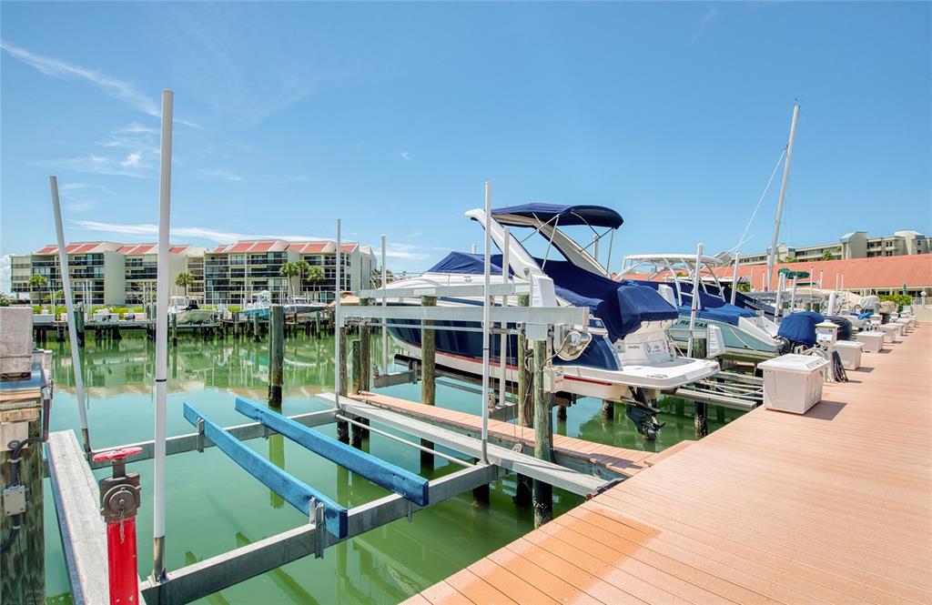 A boat lift holds a motorboat at a dock beside a calm waterway and buildings — 7984 SAILBOAT KEY BOULEVARD S UNIT 303, ST PETERSBURG, FL
