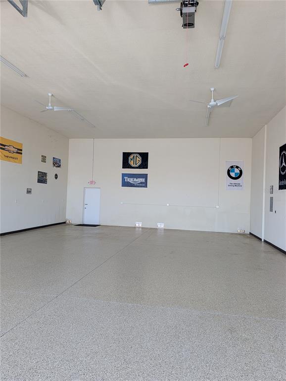 A spacious, empty garage features a speckled epoxy floor, white walls, and ceiling fans — 8290 BURNT STORE ROAD UNIT B5 and B6, PUNTA GORDA, FL