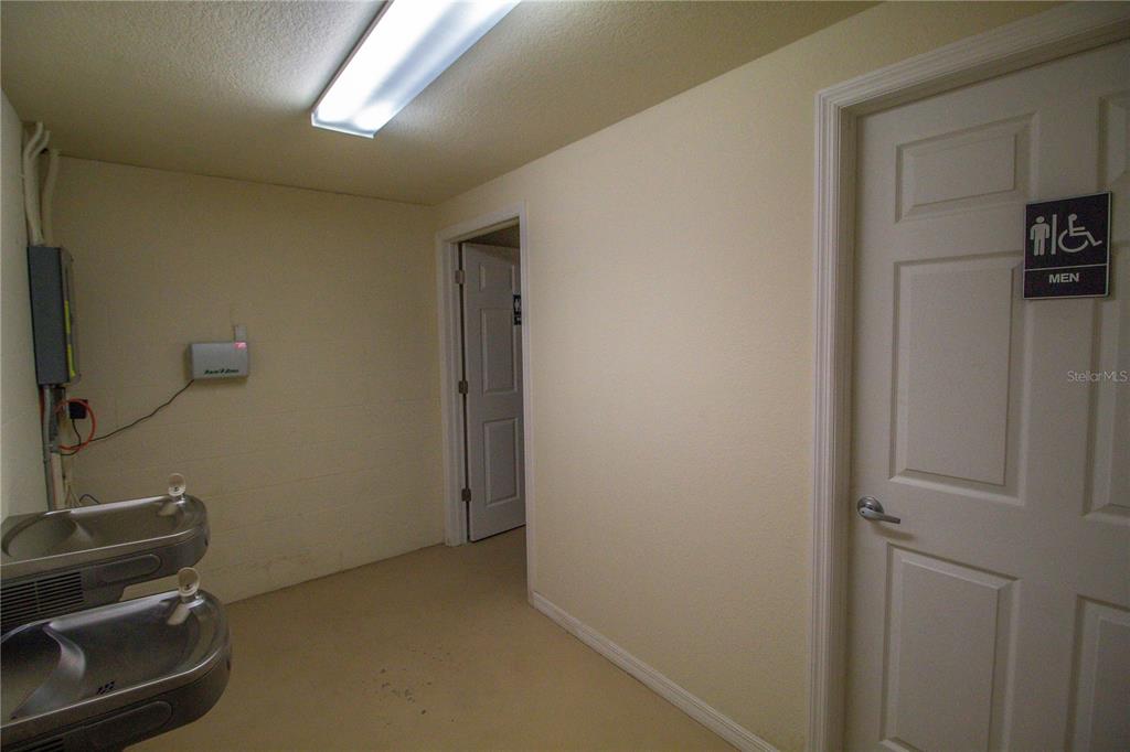 A hallway features a water fountain, a doorway, and a door labeled for a men's restroom — 8290 BURNT STORE ROAD UNIT B5 and B6, PUNTA GORDA, FL