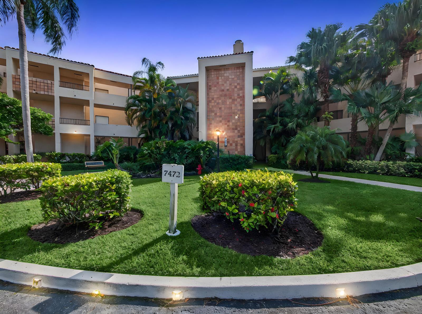 A multi-story apartment building exterior features a landscaped lawn with palm trees and bushes — 7472 La Paz Boulevard # 109, Boca Raton FL 33433, BOCA RATON, FL