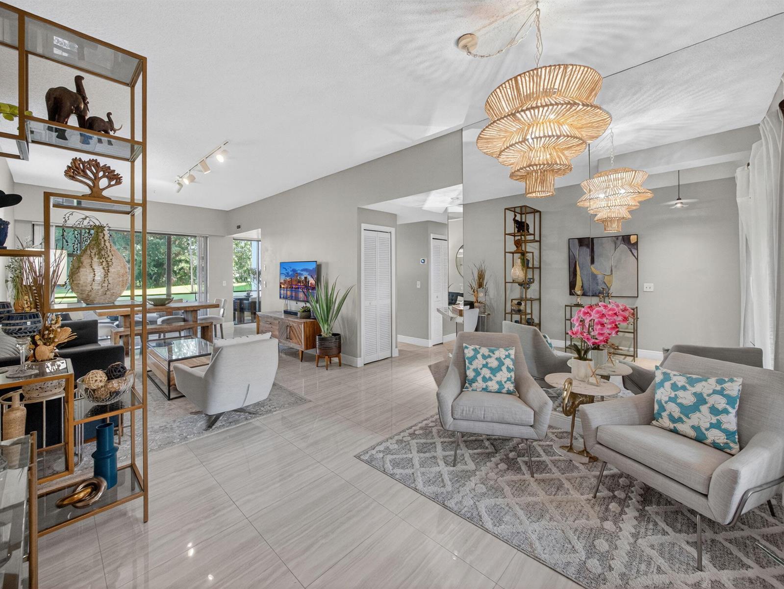 A bright, open-concept living and dining area features tile flooring, modern furniture, and tiered chandeliers — 7472 La Paz Boulevard # 109, Boca Raton FL 33433, BOCA RATON, FL
