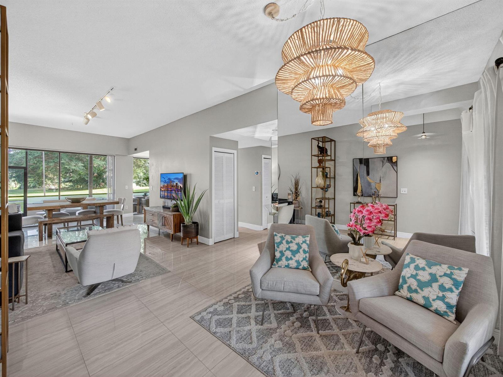 A bright, open-concept living and dining area features tile flooring, neutral walls, and tiered chandeliers — 7472 La Paz Boulevard # 109, Boca Raton FL 33433, BOCA RATON, FL