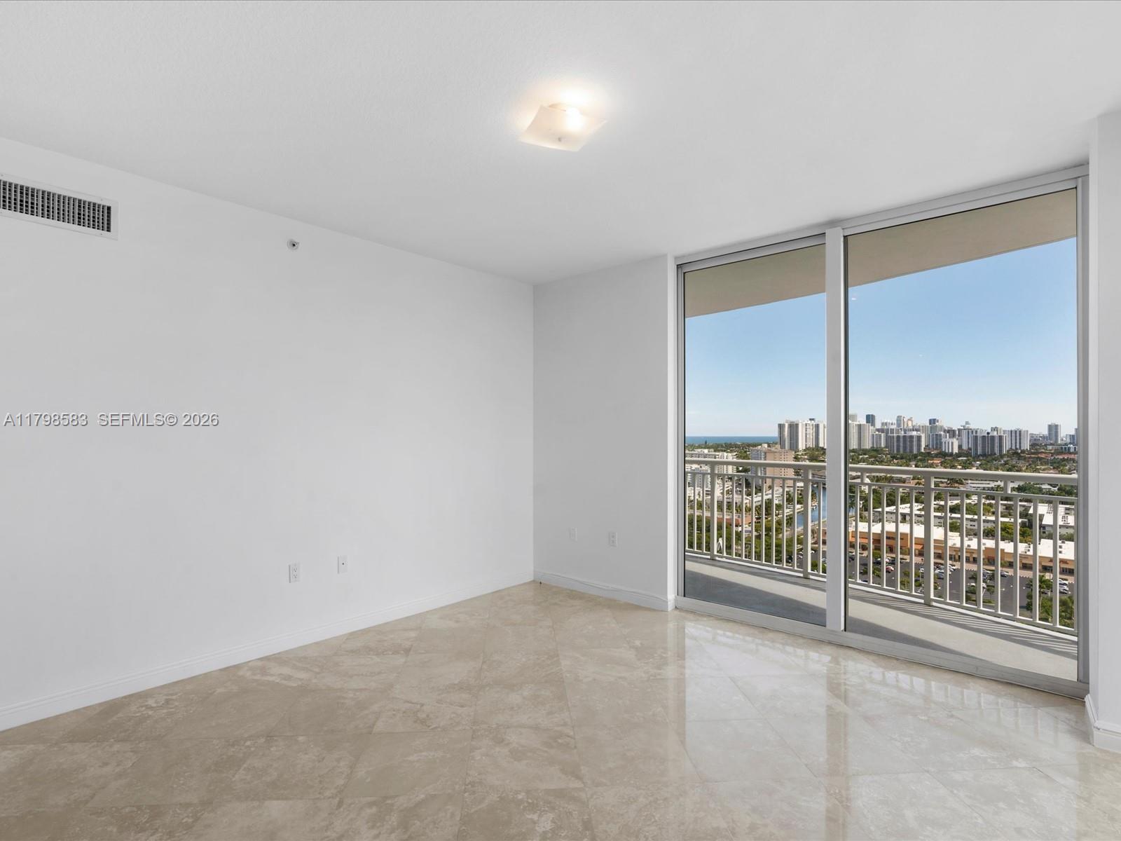 An empty room with light tile flooring, white walls, and a balcony overlooking a city — 1745 E Hallandale Beach Blvd # 2007W, Hallandale Beach FL 33009, HALLANDALE BEACH, FL
