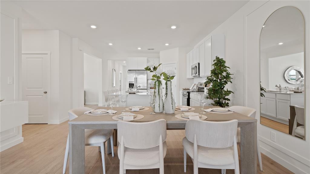 A dining area with a wooden table and chairs sits in front of a kitchen — 5395 WHISPERING GARDEN WAY, CLERMONT, FL
