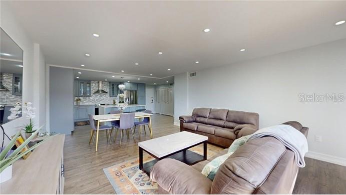 An open-concept living room features a brown sofa, a dining area, and a modern kitchen — 400 ISLAND WAY UNIT 210, CLEARWATER BEACH, FL