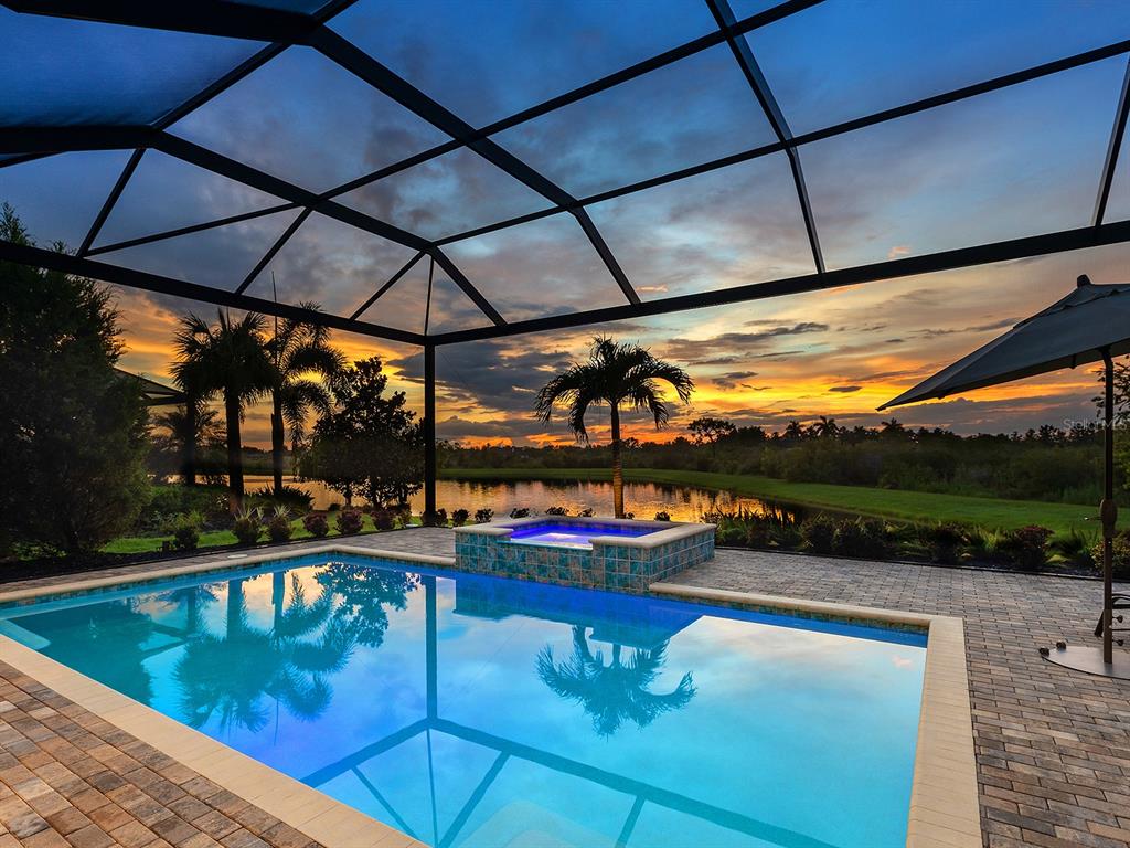 A screened-in pool and hot tub overlook a lake at sunset — 16739 VERONA PLACE, LAKEWOOD RANCH, FL