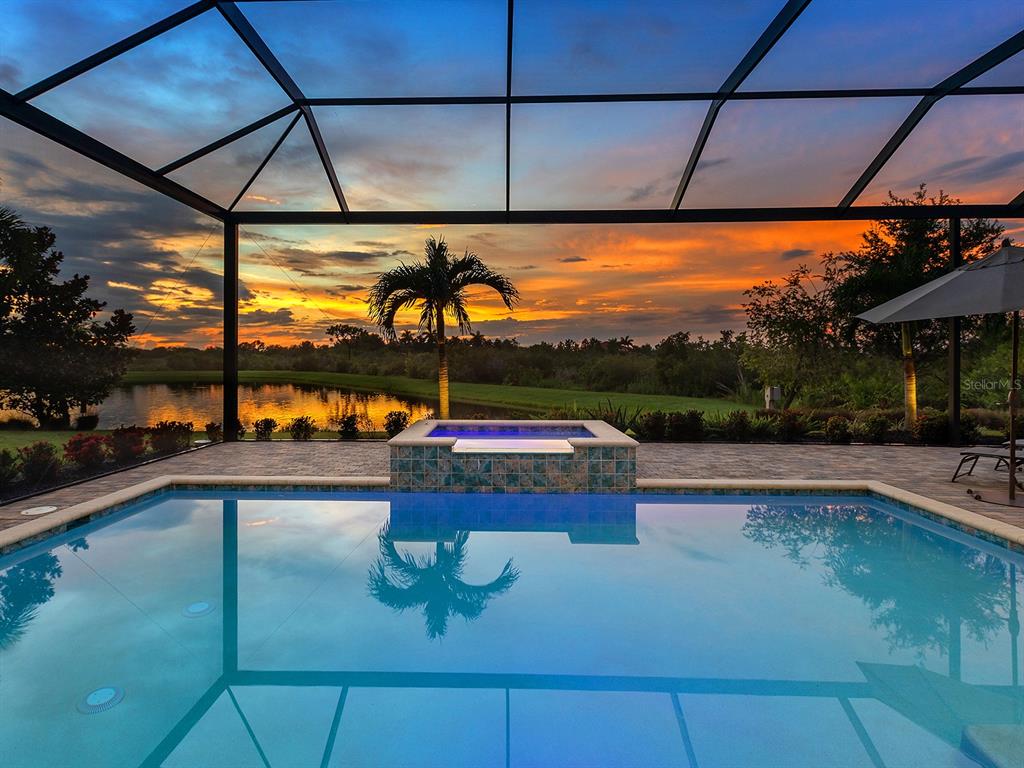 A swimming pool and spa are enclosed by a screened lanai overlooking a sunset view — 16739 VERONA PLACE, LAKEWOOD RANCH, FL