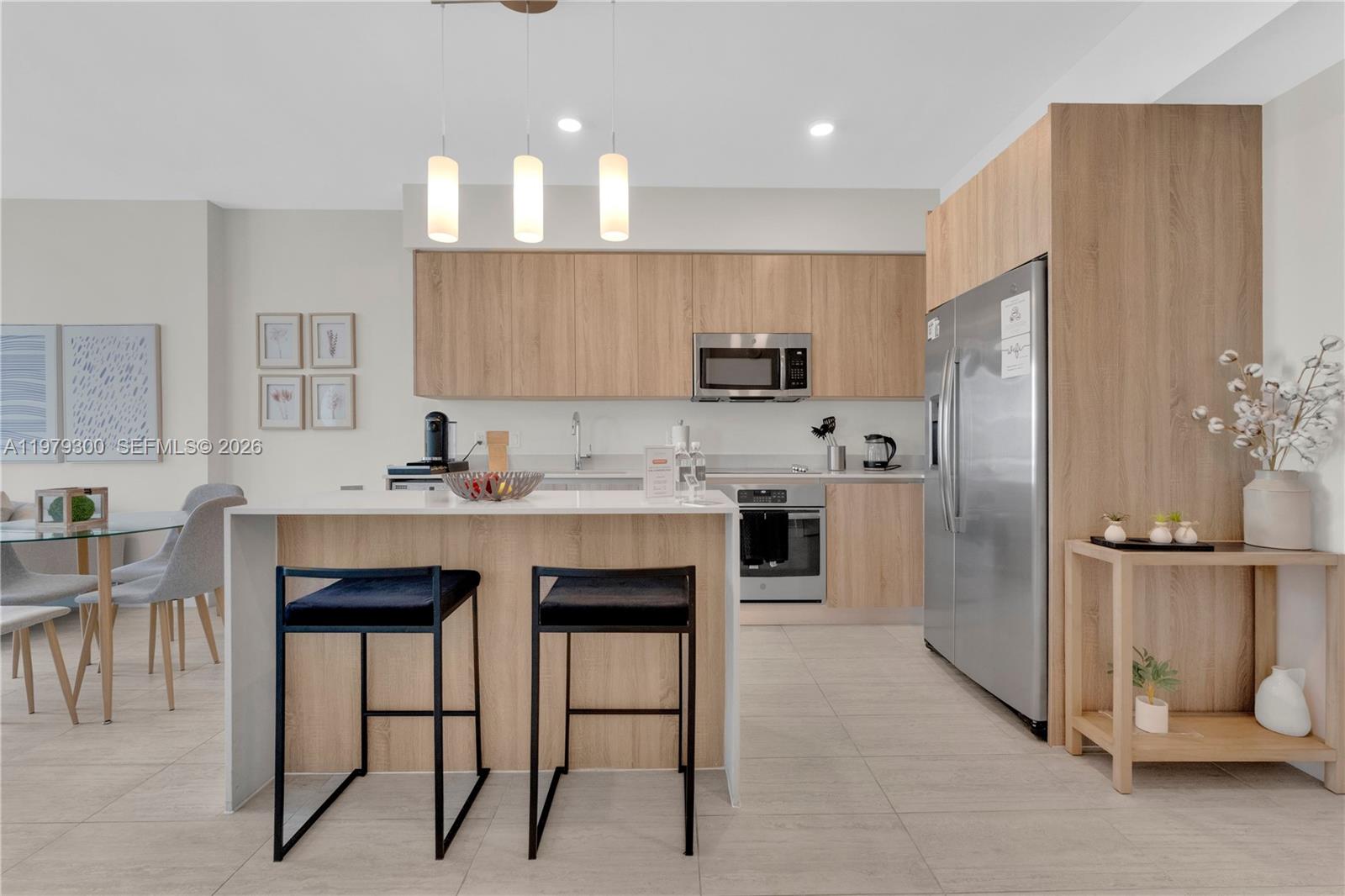 A modern kitchen features light wood cabinetry, stainless steel appliances, and a central island — 3900 Biscayne Blvd # 916, Miami FL 33137, MIAMI, FL