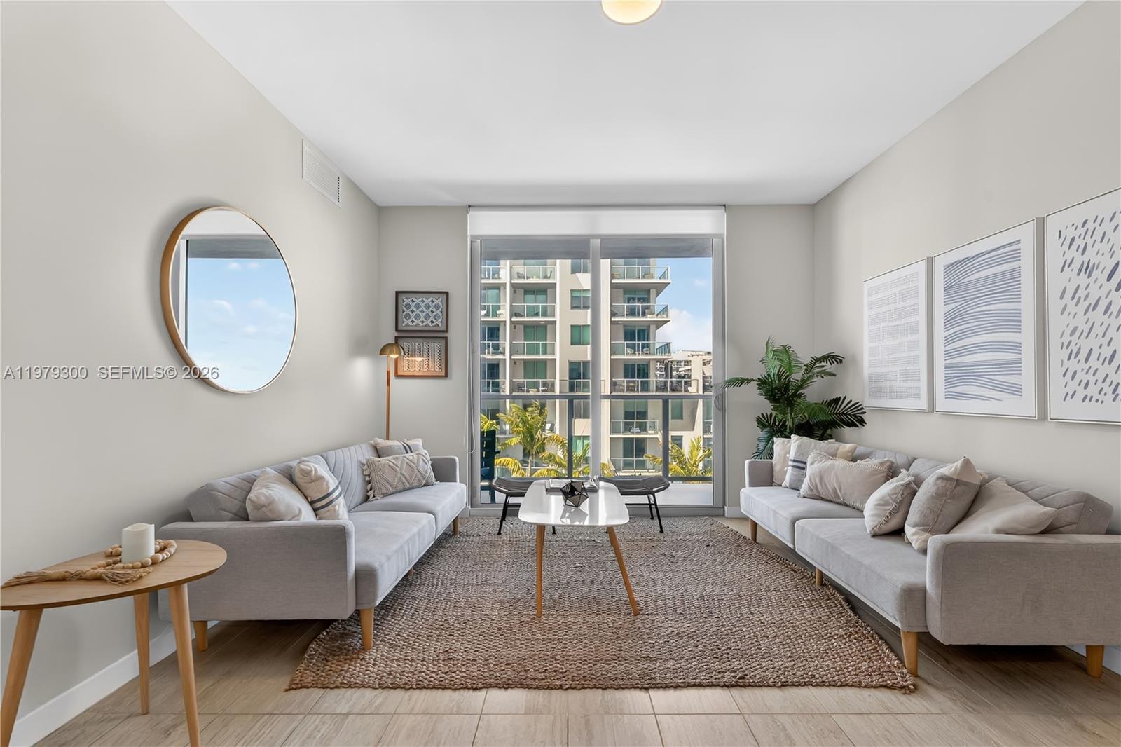 A living room features two gray sofas, a central coffee table, and a large window — 3900 Biscayne Blvd # 916, Miami FL 33137, MIAMI, FL