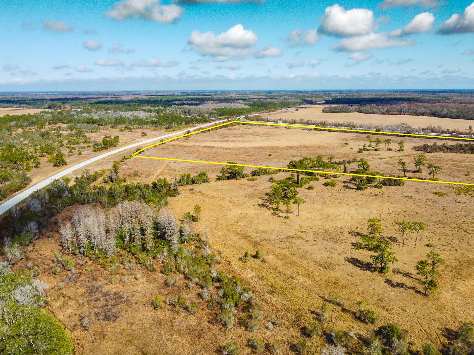 An aerial view shows a large, dry, grassy field outlined in yellow next to a road — 5001 S Kenansville Road, Okeechobee FL 34972, OKEECHOBEE, FL
