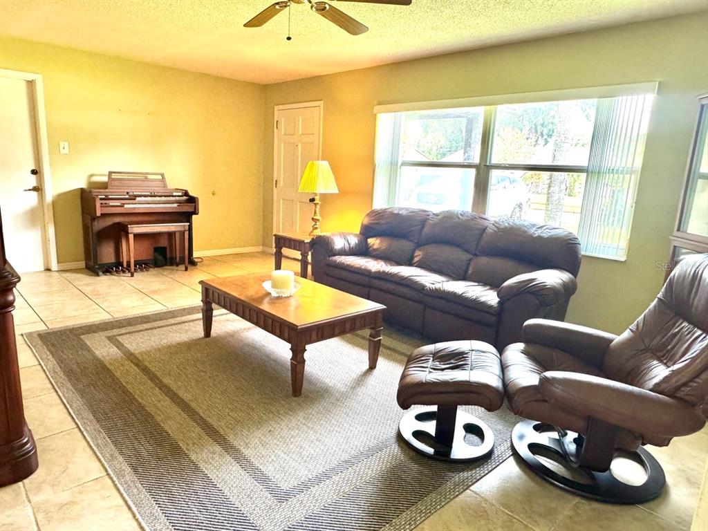 A living room features tile flooring, a brown leather sofa, a matching recliner, and an organ — 49 LAUREL OAKS CIRCLE, ORMOND BEACH, FL