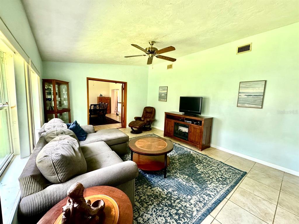 A living room features a sectional sofa, a coffee table, a television console, and tile flooring — 49 LAUREL OAKS CIRCLE, ORMOND BEACH, FL