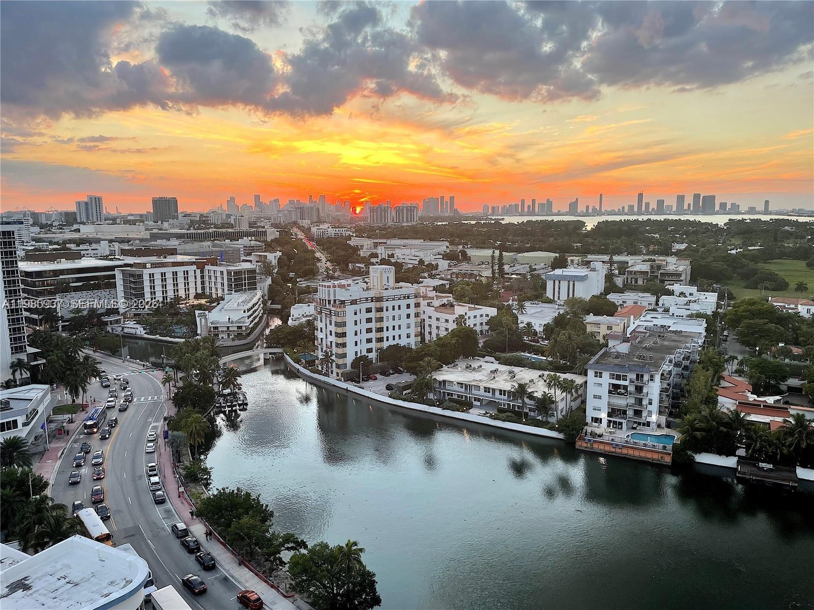 An elevated view shows a sunset over a city skyline, a canal, and surrounding buildings — 2555 Collins Ave # 2002, Miami Beach FL 33140, MIAMI BEACH, FL