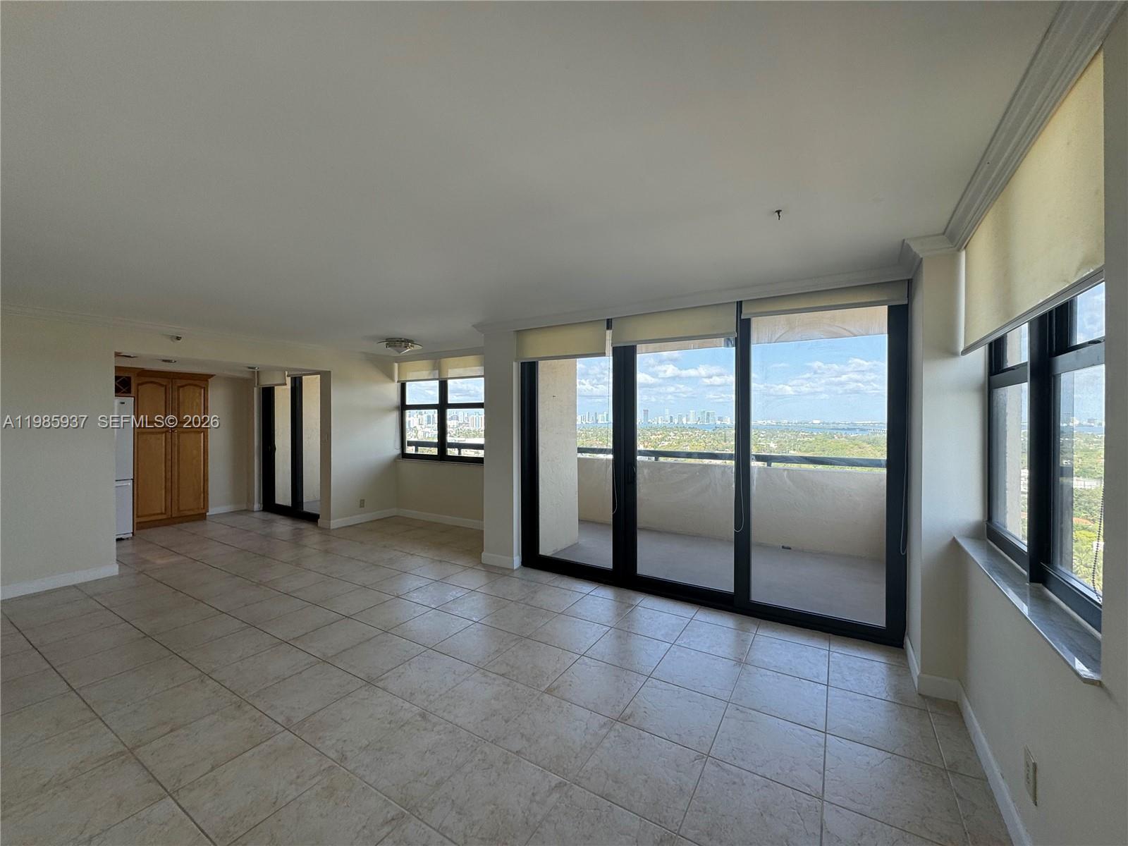 An empty living room features light tile flooring, large sliding glass doors, and a balcony view — 2555 Collins Ave # 2002, Miami Beach FL 33140, MIAMI BEACH, FL