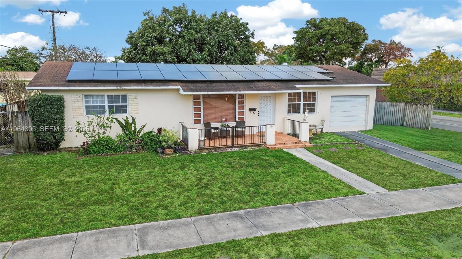 A single-story house features a solar panel roof, a front porch, and an attached garage — 1110 NE 204th Ter, Miami FL 33179, MIAMI, FL