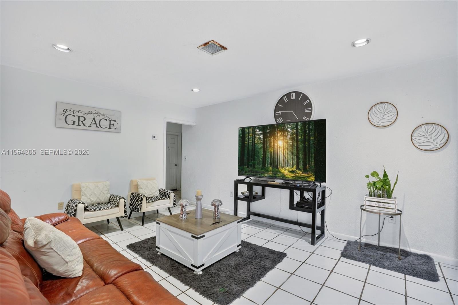 A living room features a leather sofa, two armchairs, a coffee table, and a television — 1110 NE 204th Ter, Miami FL 33179, MIAMI, FL
