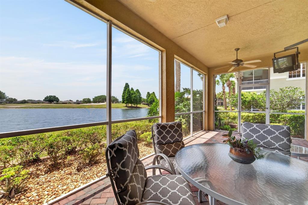 A screened-in patio features a glass table, patterned chairs, and a view of a lake — 1364 EMERALD DUNES DRIVE, SUN CITY CENTER, FL
