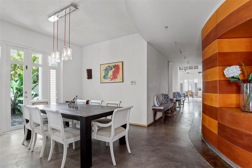 A dining room with a dark wood table, white chairs, and a curved wood wall — 2003 ESPANA, SAN JUAN, PR