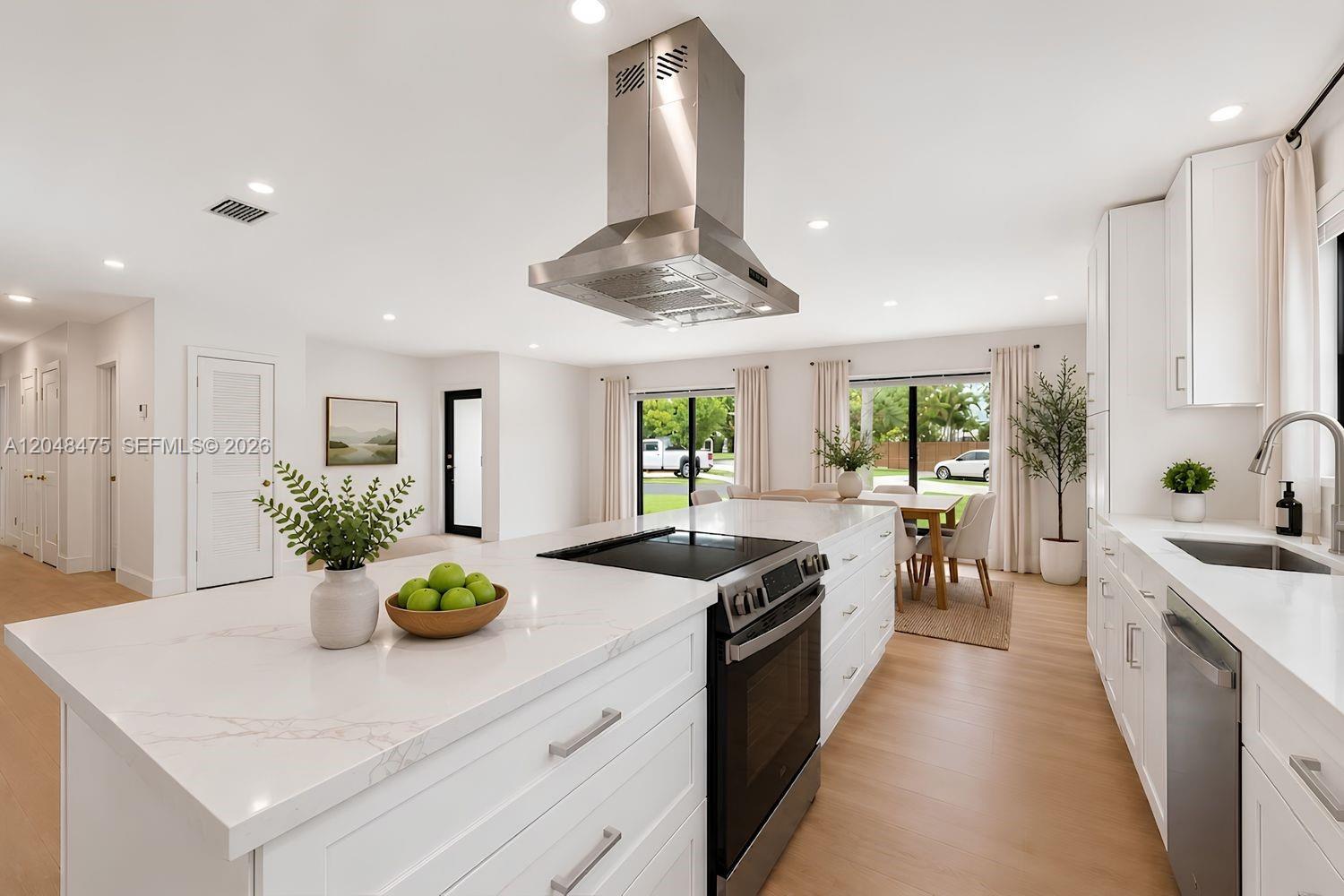 A modern white kitchen features a large island with a cooktop and stainless steel hood — 18451 SW 90th Ave, Cutler Bay FL 33157, CUTLER BAY, FL
