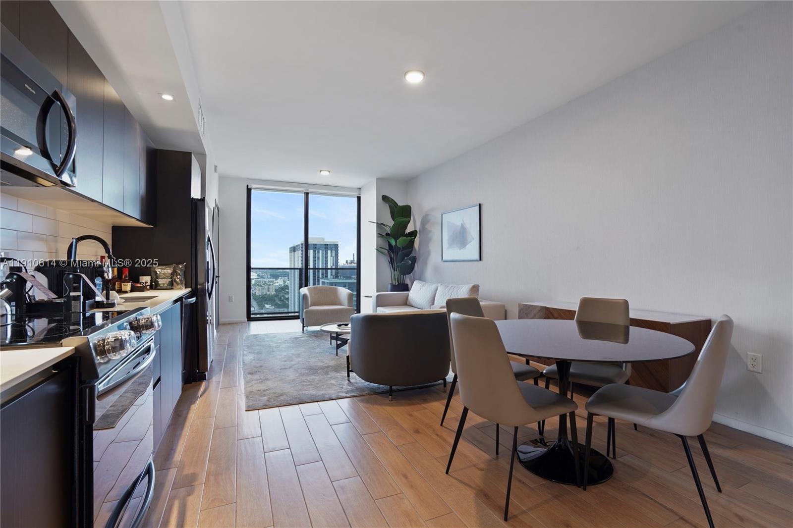 An open-concept living and dining area features wood-look flooring, dark cabinetry, and floor-to-ceiling windows — 398 NE 5th St # 3618, Miami FL 33132, MIAMI, FL