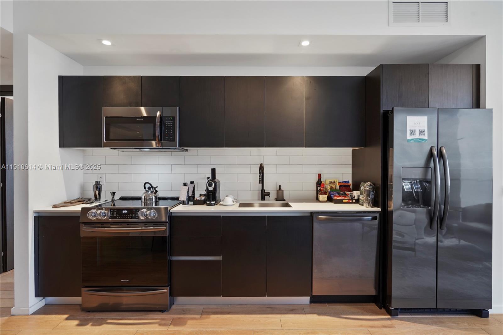 A modern kitchen features dark wood cabinetry, stainless steel appliances, and a white subway tile backsplash — 398 NE 5th St # 3618, Miami FL 33132, MIAMI, FL