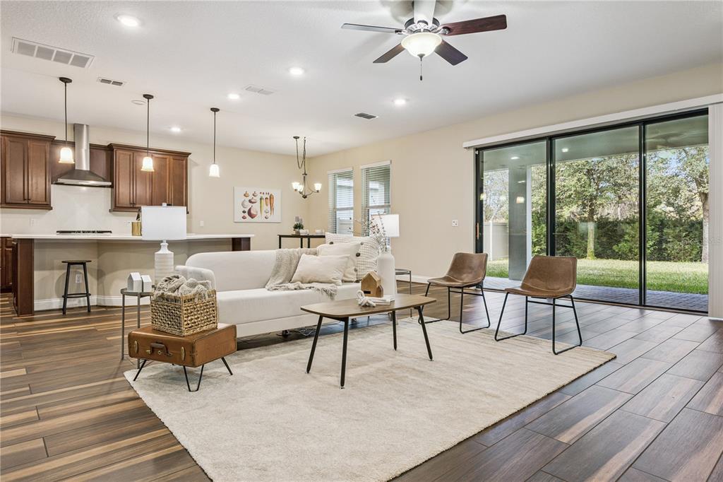 An open-concept living room and kitchen feature wood-look tile flooring and sliding glass doors — 13525 GORGONA ISLE DRIVE, WINDERMERE, FL