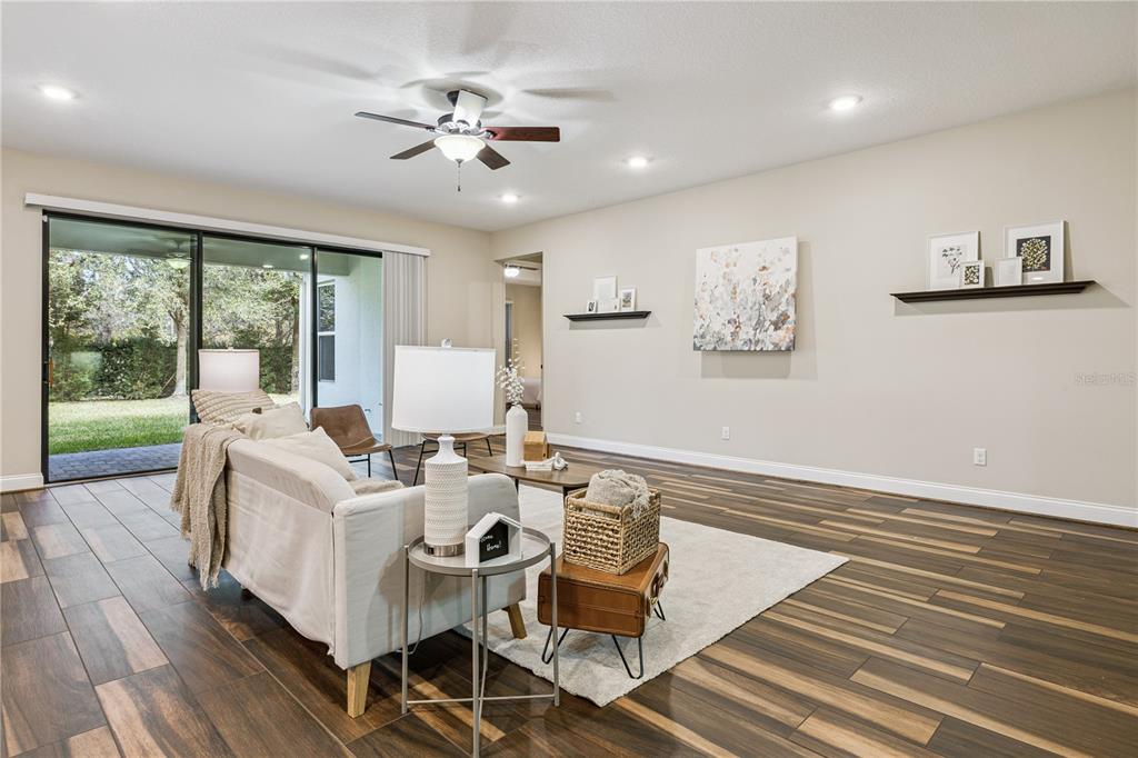 A living room features wood-look tile flooring, a ceiling fan, and sliding glass patio doors — 13525 GORGONA ISLE DRIVE, WINDERMERE, FL