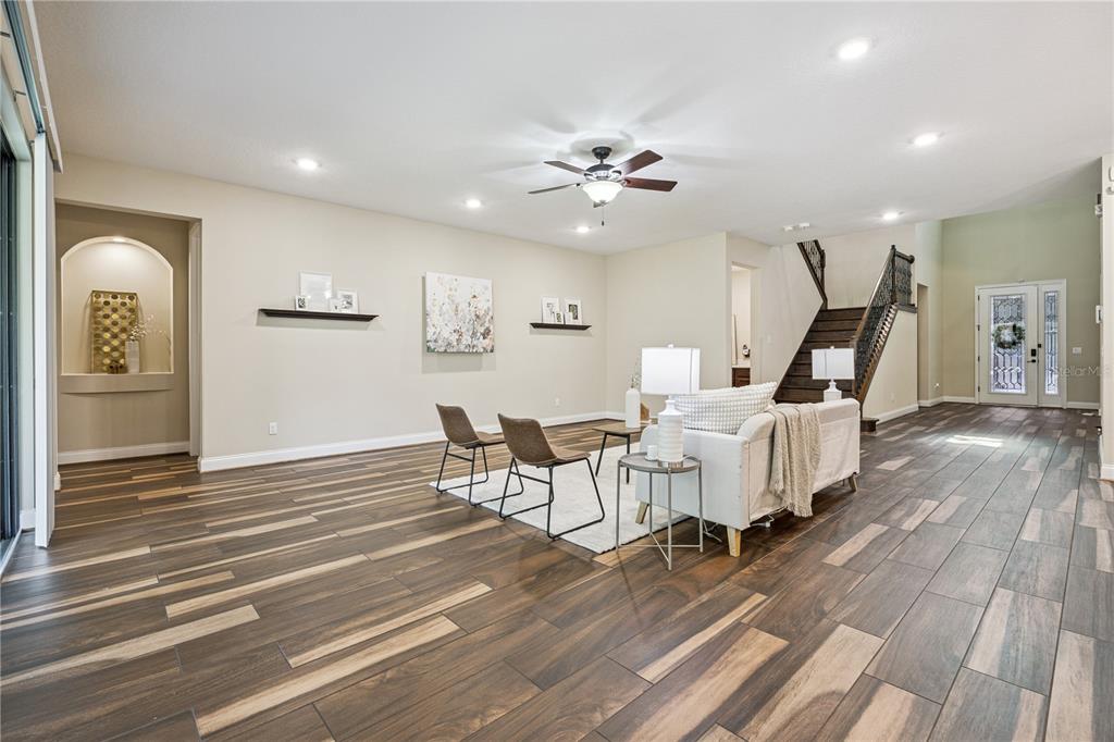 A spacious living room features wood-look tile flooring, a staircase, and a ceiling fan — 13525 GORGONA ISLE DRIVE, WINDERMERE, FL