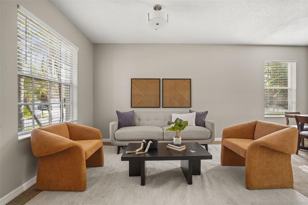 A living room features a grey sofa, two orange armchairs, and a black coffee table — 14837 HUNTLEY DRIVE, ORLANDO, FL